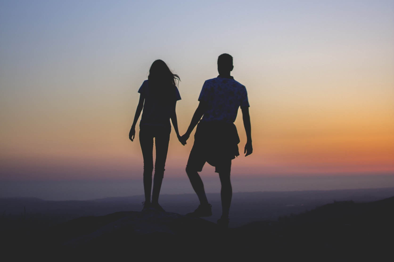 Coppia che si tiene per mano al tramonto