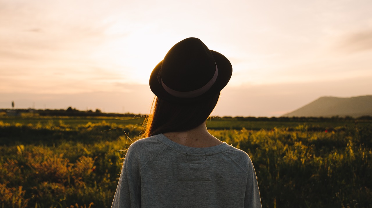 ragazza con cappello di spalle che ammira l'orizzonte