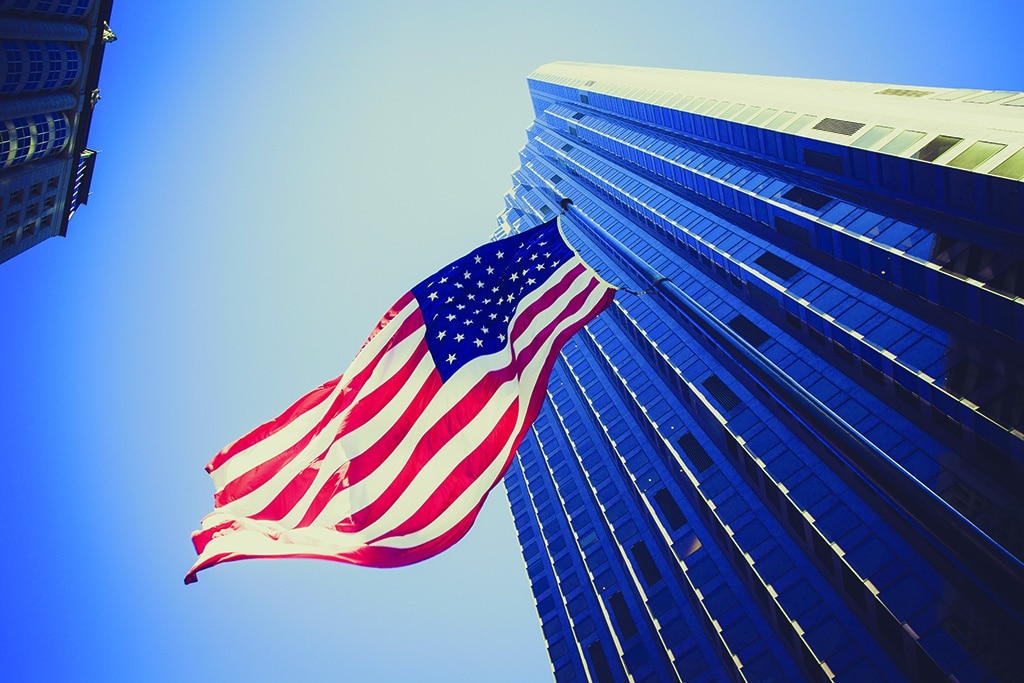 Grattacielo ripreso dal basso con bandiera americana