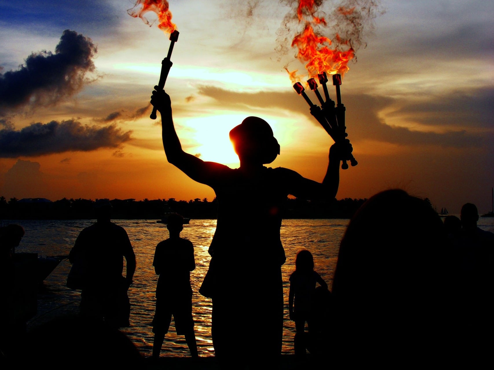 persone con fiaccole in mano sulla spiaggia al tramonto