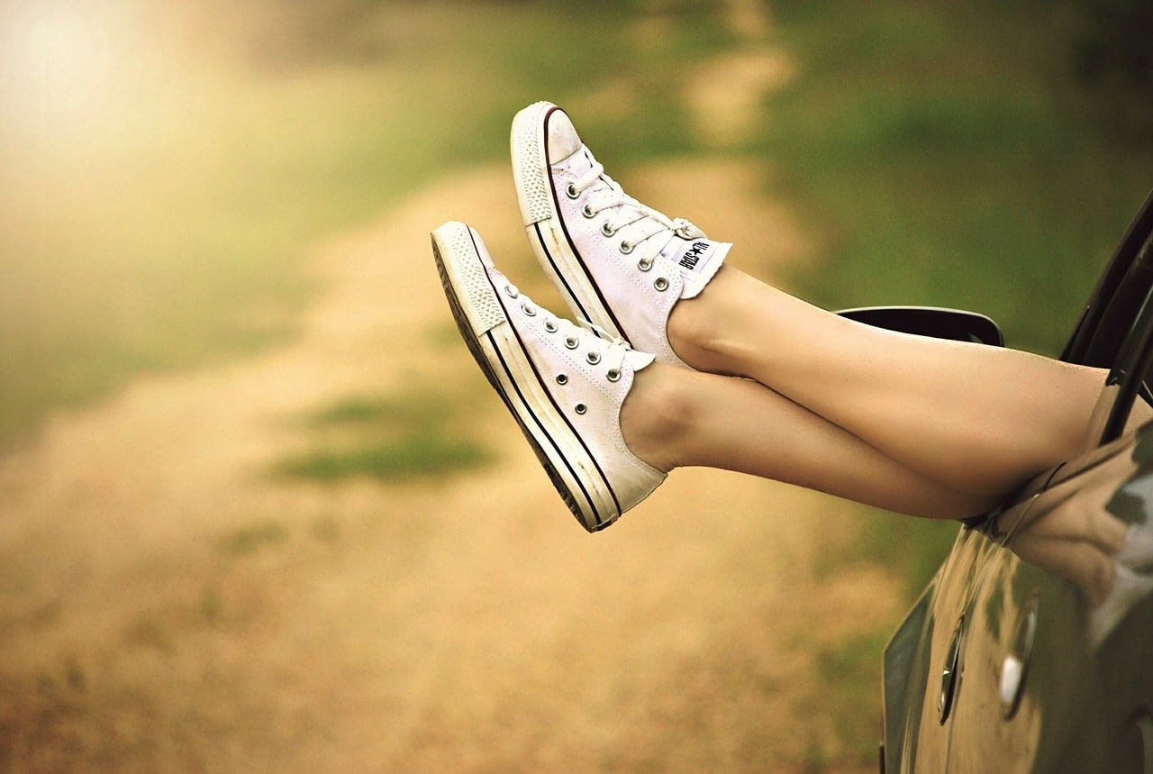 Gambe incrociate con scarpe converse bianche ai piedi