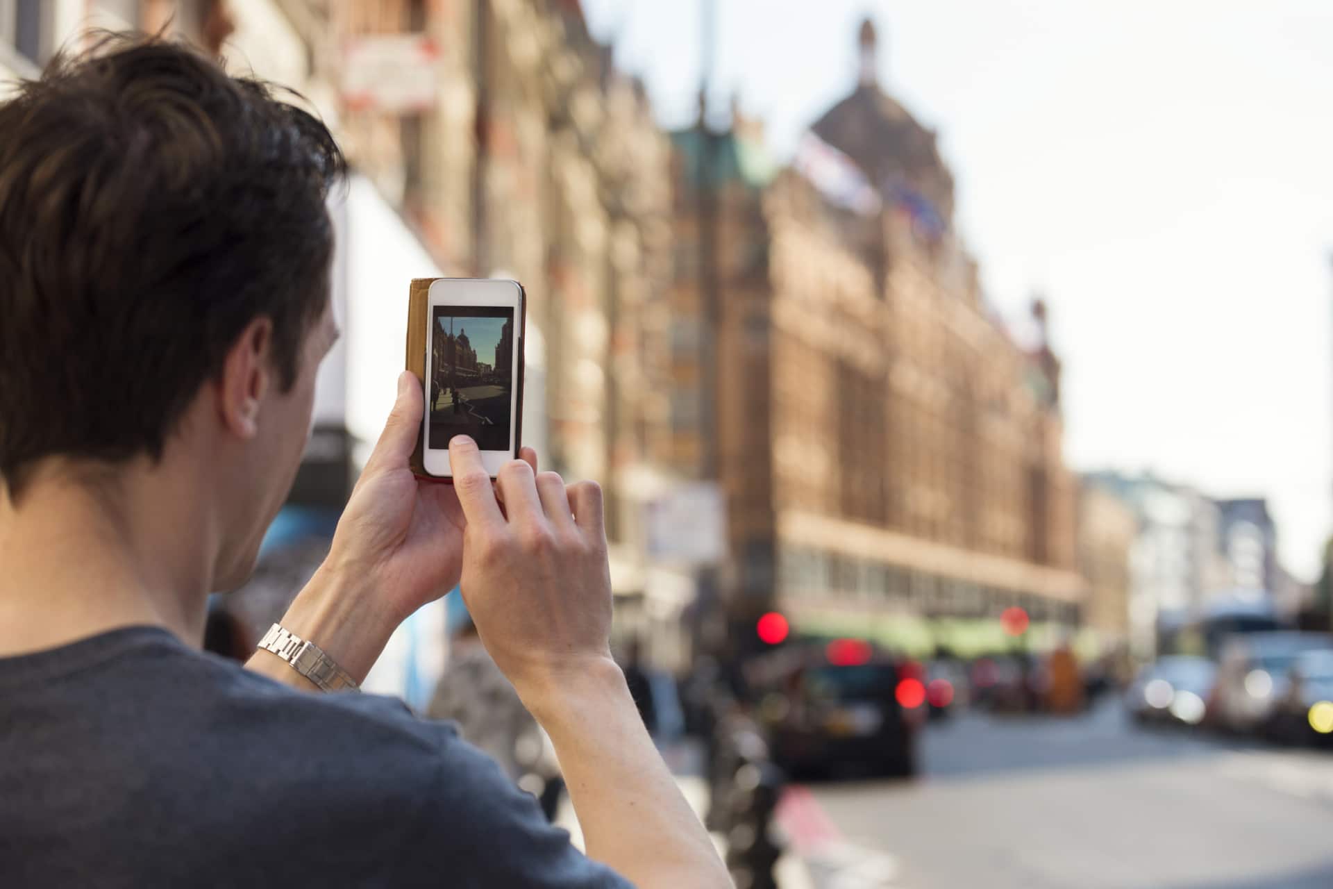 Ragazzo di spalle che fotografa Harrods dal cellulare
