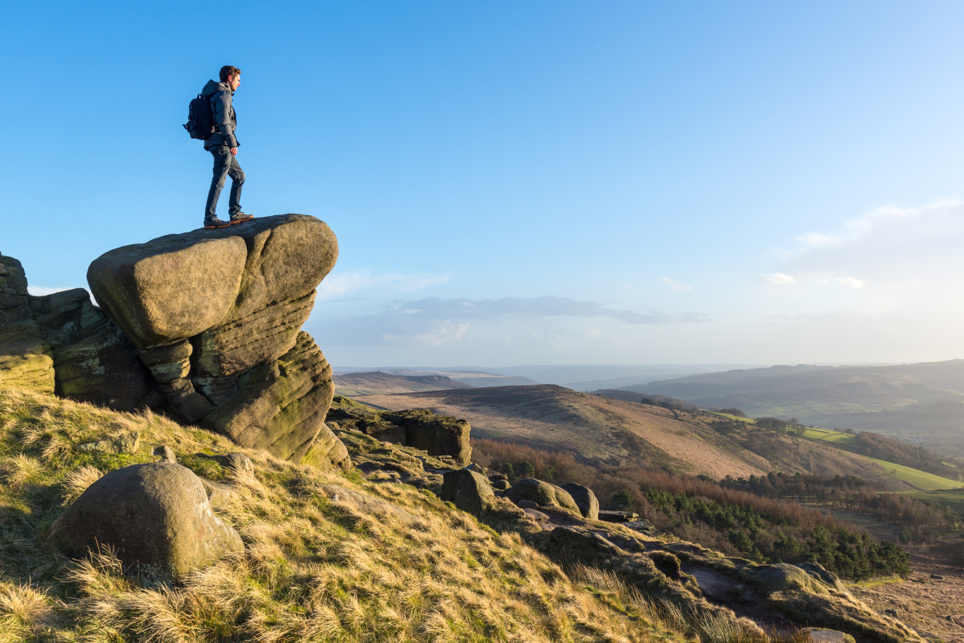 Young male hiker stood on rocky outcrop