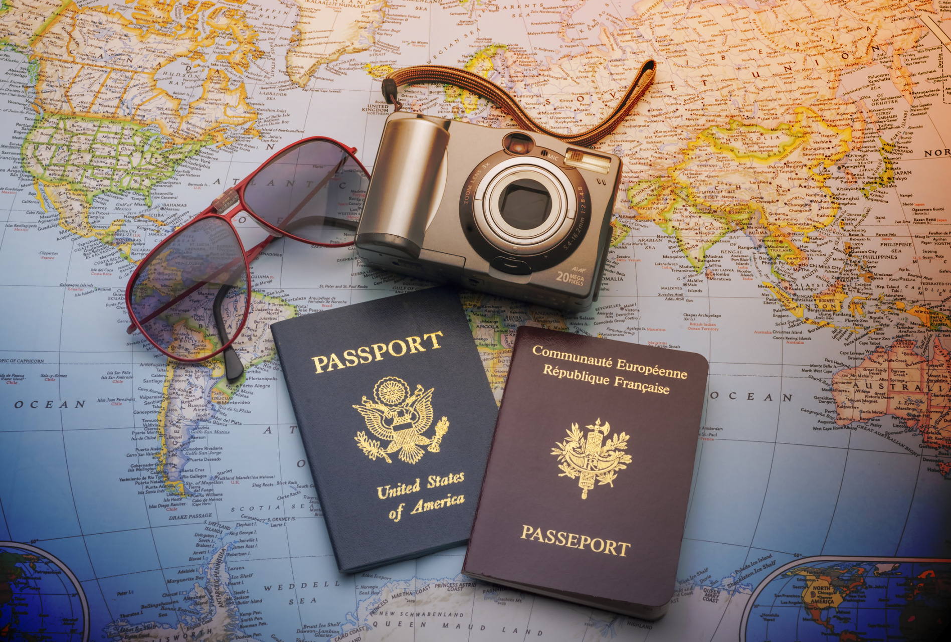 Cartina con passaporto, macchina fotografica e occhiali da sole