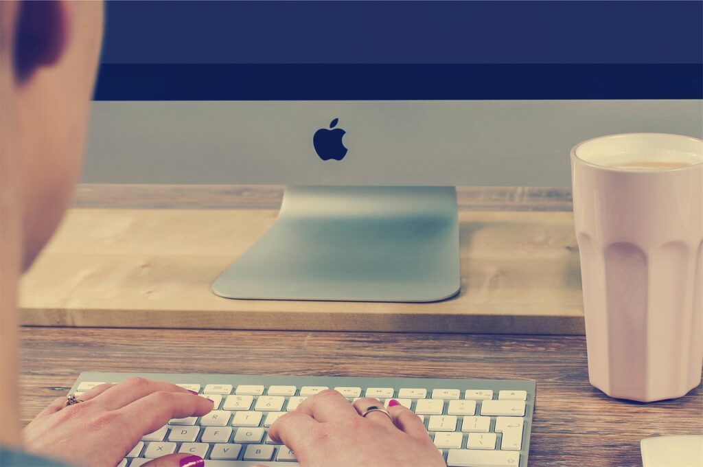 Persona che scrive alla tastiera di un Mac