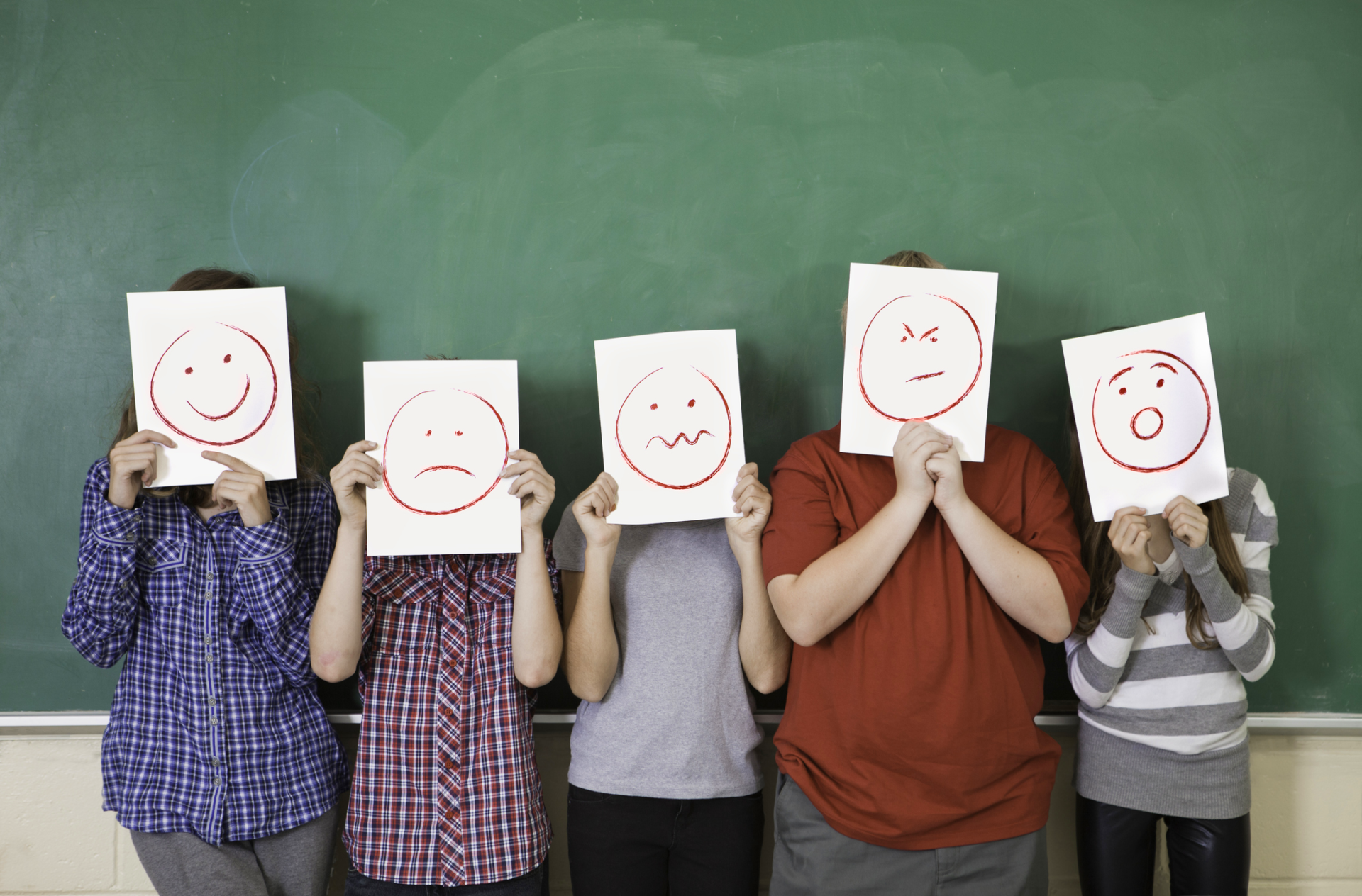 Bambini con faccine disegnate su fogli davanti al viso