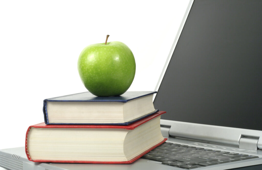 Notebook con libri sulla tastiera e mela verde