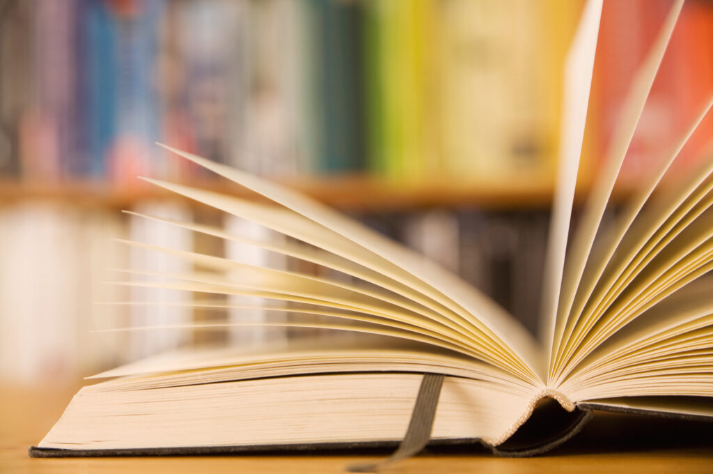 Libro con pagine aperte e libreria sullo sfondo