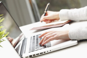 Mano che scrive al pc e prende appunti