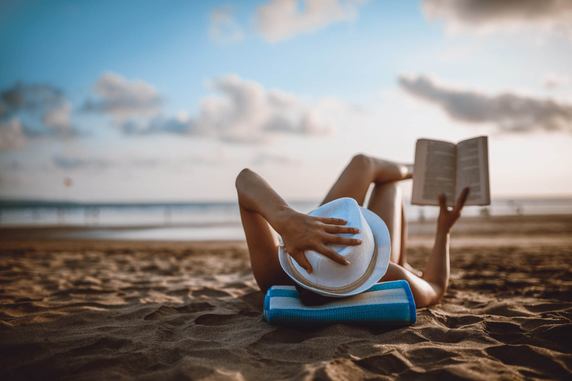 Donna che legge un libro sdraiata sulla spiaggia