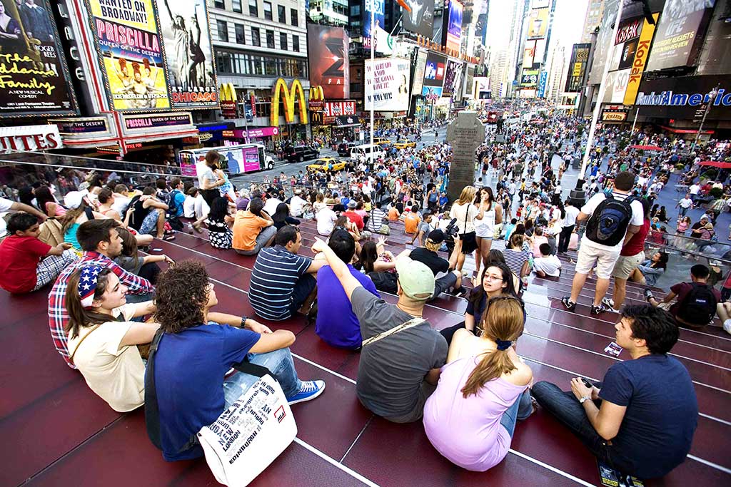 ragazzi in vacanza studio seduti sulle scale a Times Square
