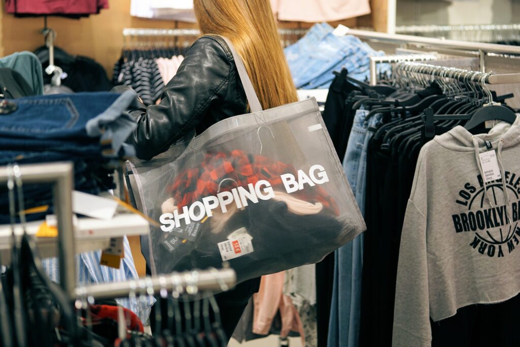 Donna che fa shopping in negozio con shopping bag sulla spalla