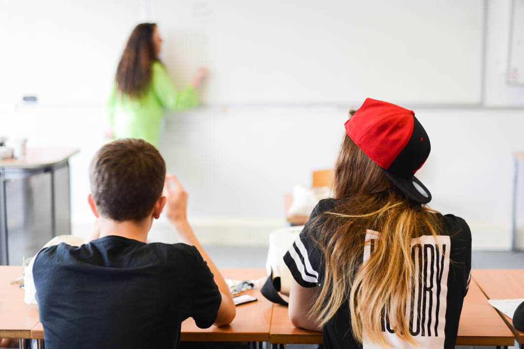 Studenti di spalle in classe che seguono la lezione