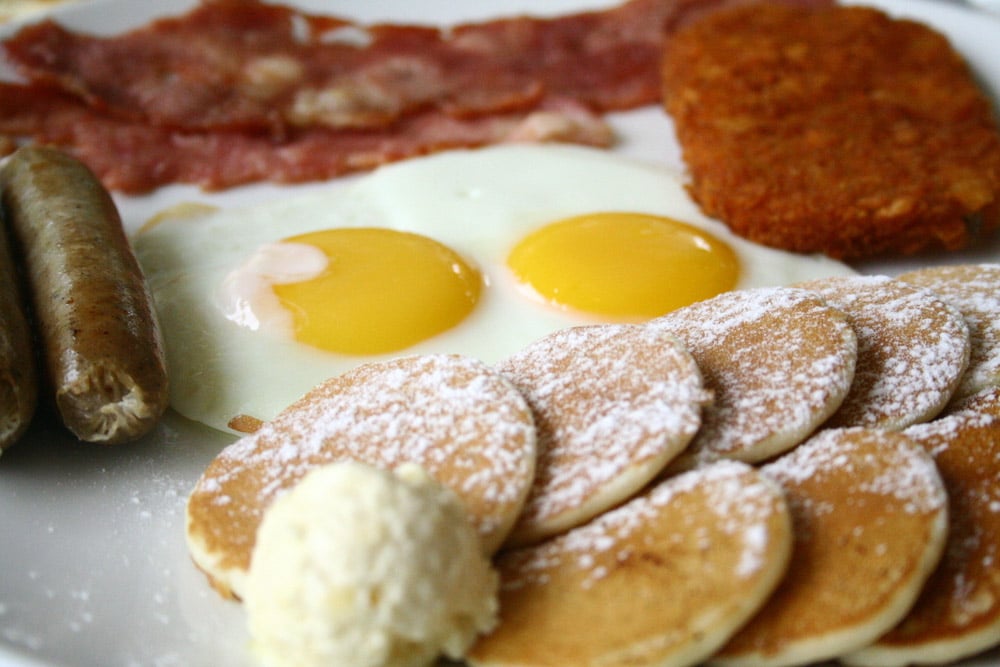 Colazione inglese pancetta, uova strapazzate, salsicce, pancakes