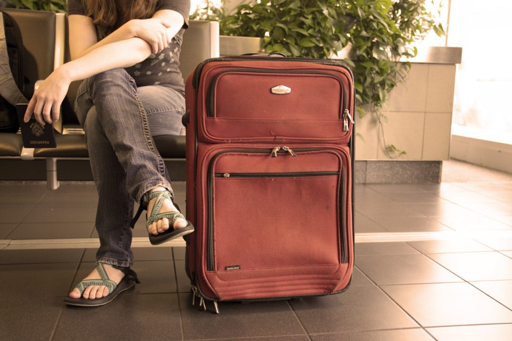 Ragazza in attesa in aeroporto con la valigia