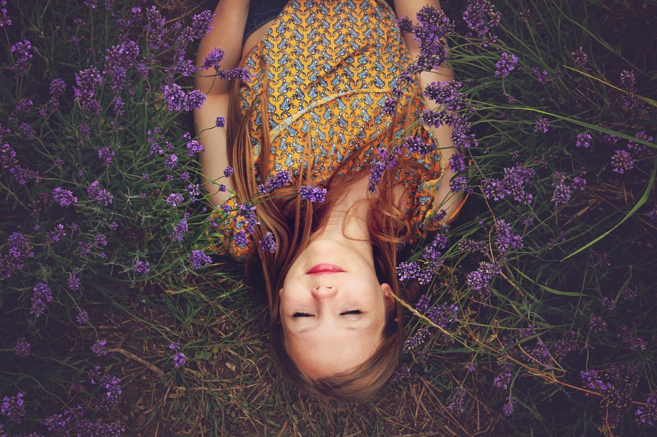 ragazza che dorme sdraiata un prato con fiori viola