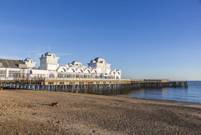 South Parade Pier, Southsea, Hampshire, southern England, UK, with stony pebble  under a clear blue sky