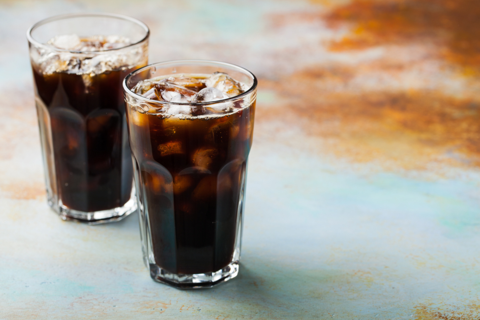 Il 4 luglio, The Independence Day Ice coffee in a tall glass with cream poured over and coffee beans. Cold summer drink on a blue rusty background with copy space