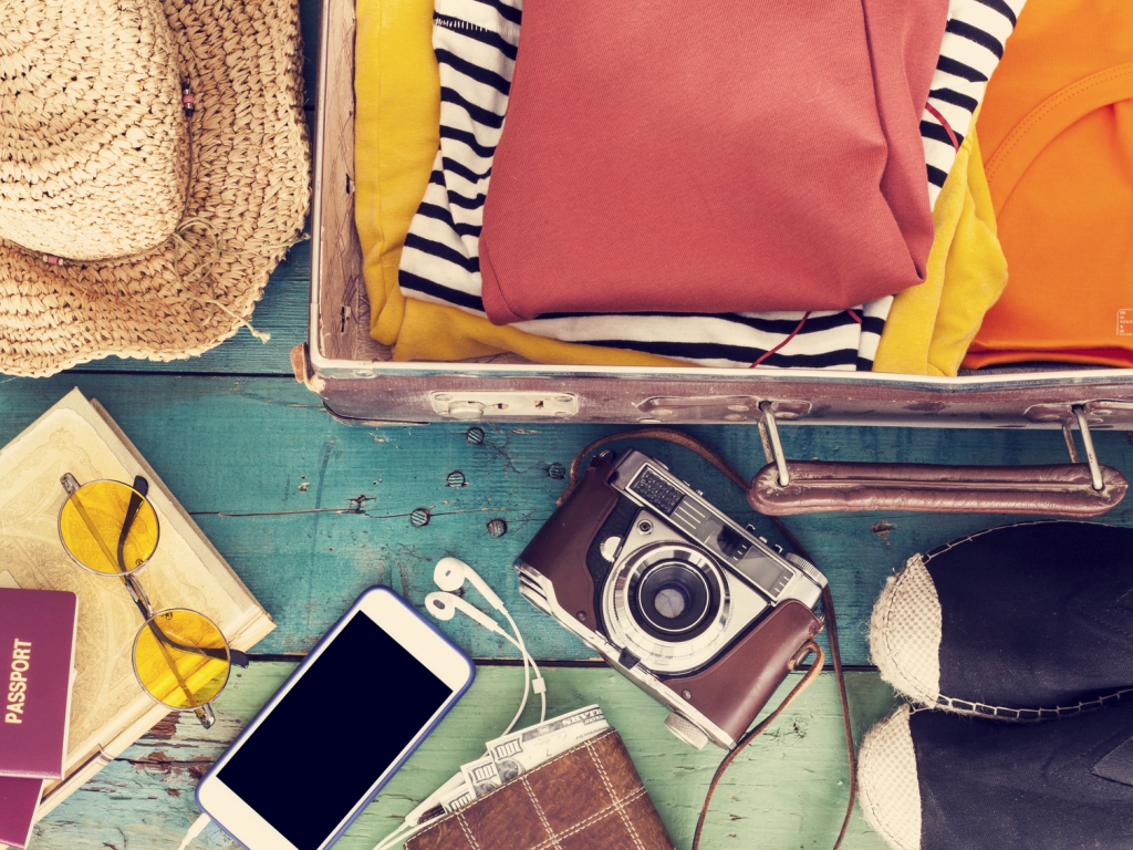 Bagaglio a mano: cosa portare e cosa è vietato Bagaglio a mano aperto con macchina fotografica, documenti di viaggio, occhiali, cappello, smartphone