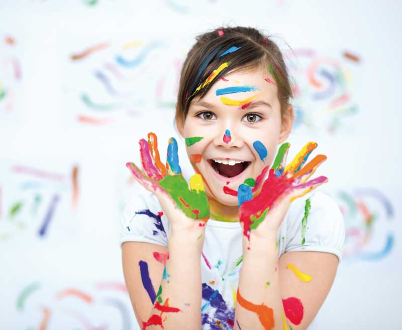 Vacanze studio in Italia: il suo primo viaggio da “grande” Bambina sorridente con mani e viso sporchi di pittura colorata