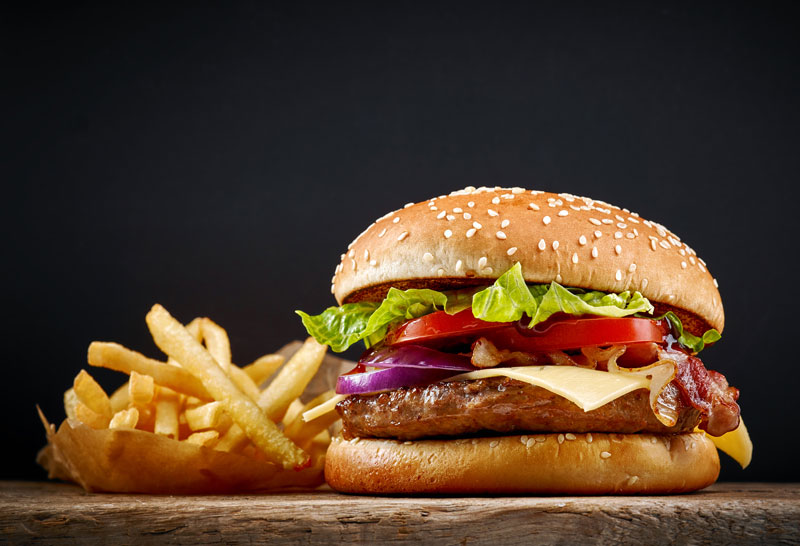 Stereotipi sugli americani: saranno veri? Panino con hamburger, cipolle e pomodori e patatine fritte