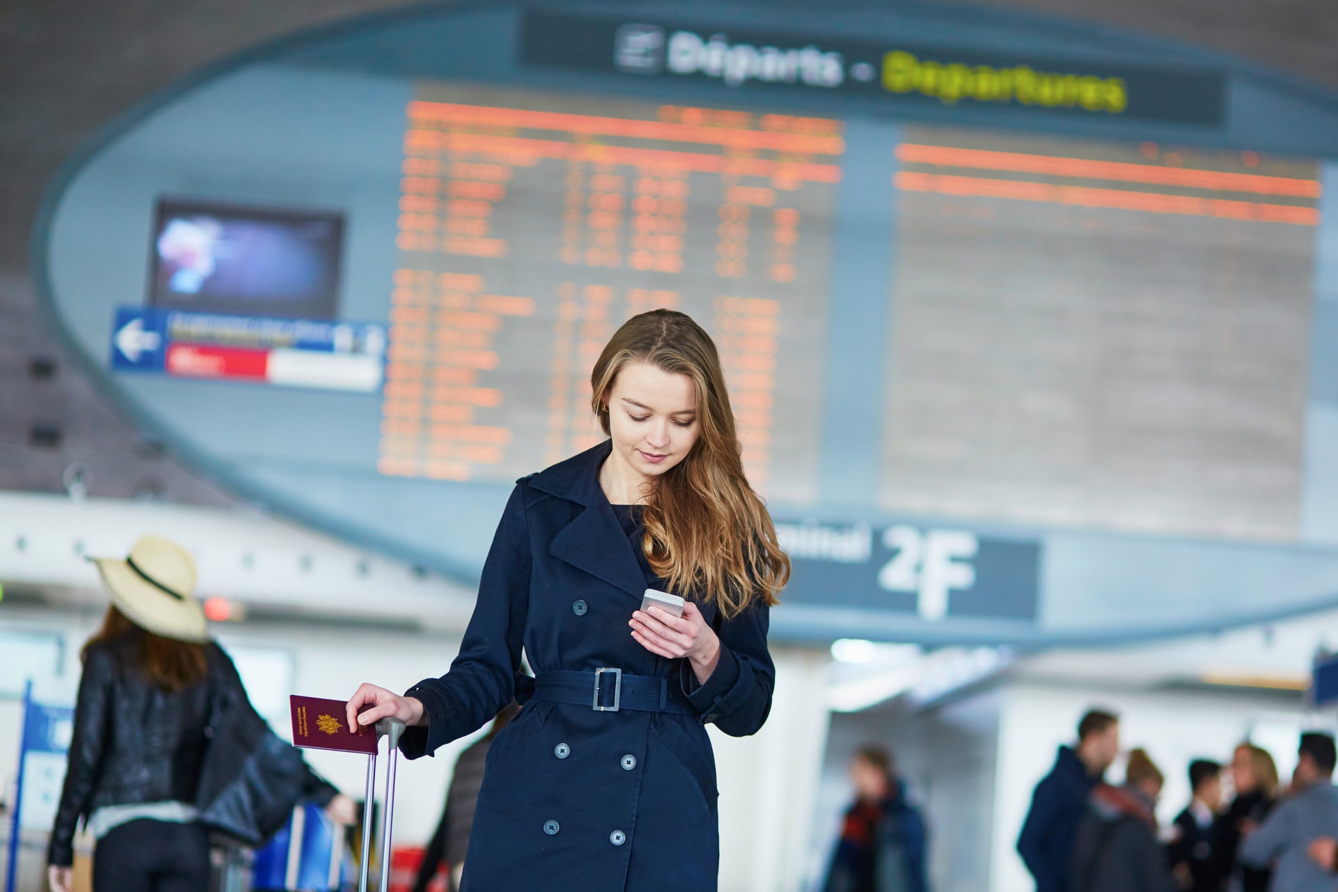 Perchè bisogna spegnere il cellulare in aereo? Ragazza in aeroporto con smartphone