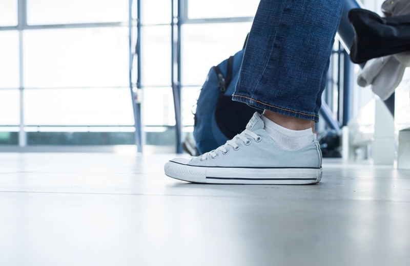 Come vestirsi in aeroporto: comodi ma con stile Piedi persona seduta in aeroporto, con sneakers