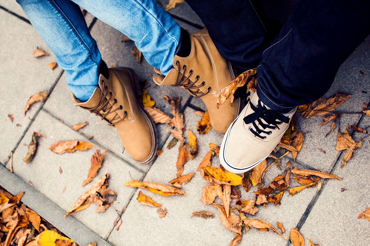 Una lezione di inglese sulle scarpe Due paia di piedi con stivali e sneakers