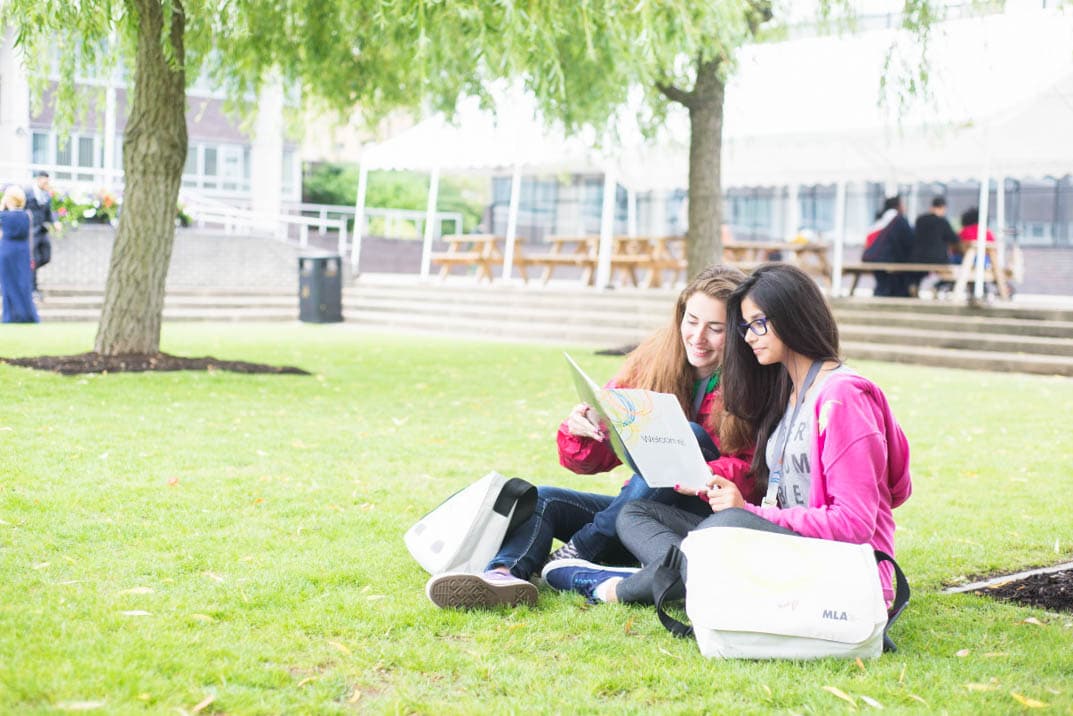 Cose delle scuola inglese che stupiranno tutti Due studentesse MLA sedute sul prato nel campus